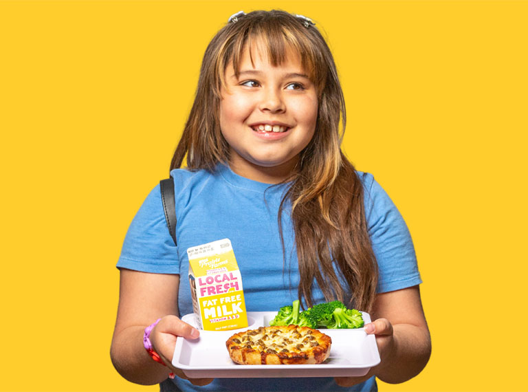 young girl with pizza and milk on a school lunch tray