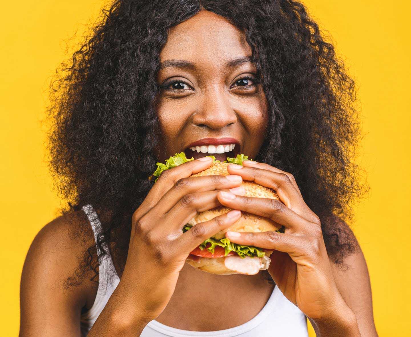 happy woman biting into a burger